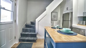 A modern kitchen with a wooden island, stainless steel appliances, and a staircase leading to another level.