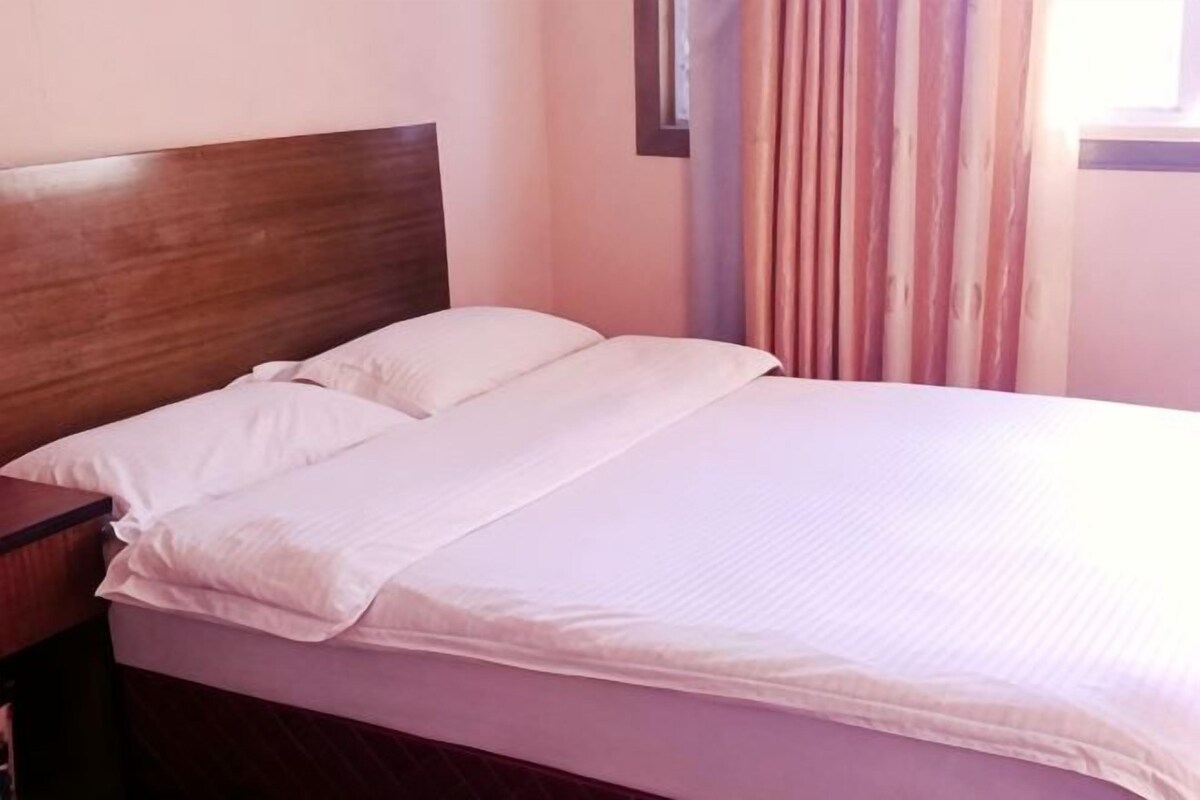 A bed with a wooden headboard, white bedding, and a nightstand.