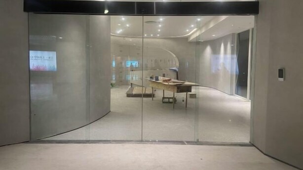 A modern interior with a curved glass wall, recessed lighting, and a table with papers. - Jinju Hostel (Shanghai)
