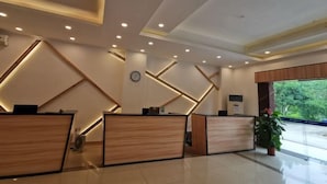 A modern reception area with geometric wall designs, wooden reception desks, and a clock on the wall. - Jiayiyuan Farm (Kaiping)