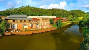 A riverside hotel with a large building, a wooden deck, and a river. - Jiayiyuan Farm (Kaiping)