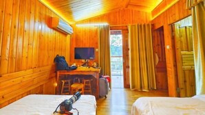 A wooden cabin room with two beds, a desk with a chair, a television, and a window with curtains. - Jiayiyuan Farm (Kaiping)