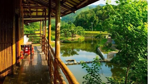 A wooden deck with a view of a pond and greenery. - Jiayiyuan Farm (Kaiping)