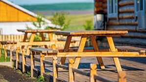 Wooden picnic tables arranged on a wooden deck outside a log cabin. - Erguna Shiwei Radio & Tv Hotel (Ergun)