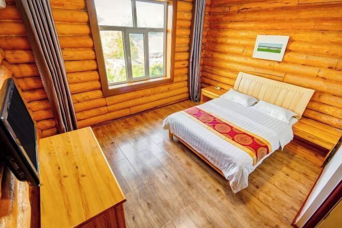 Un dormitorio de estilo cabaña de madera con una cama, una mesa de madera y una ventana.