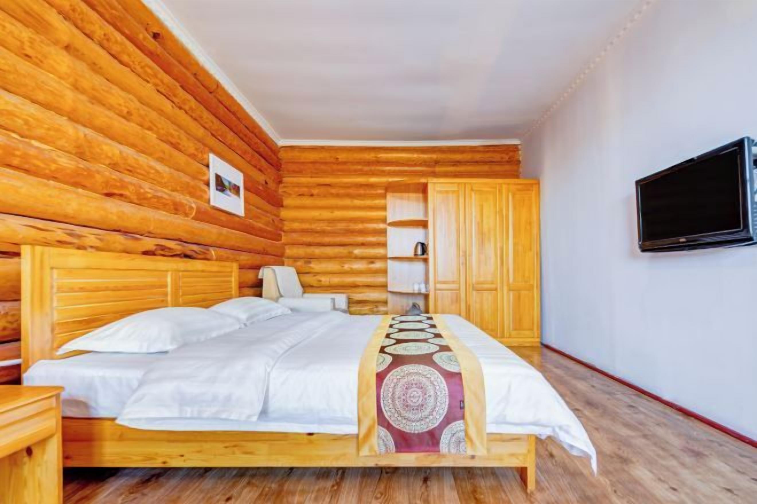 A wooden-paneled room with a bed, a TV, and a wardrobe.