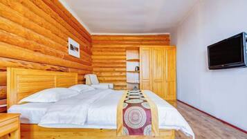 A wooden-paneled room with a bed, a TV, and a wardrobe.
