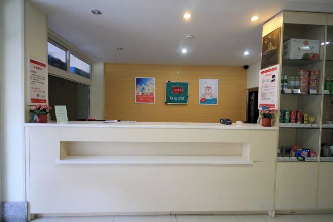 Una mesa de recepción con mostrador, un tablón de anuncios y un estante con objetos varios.