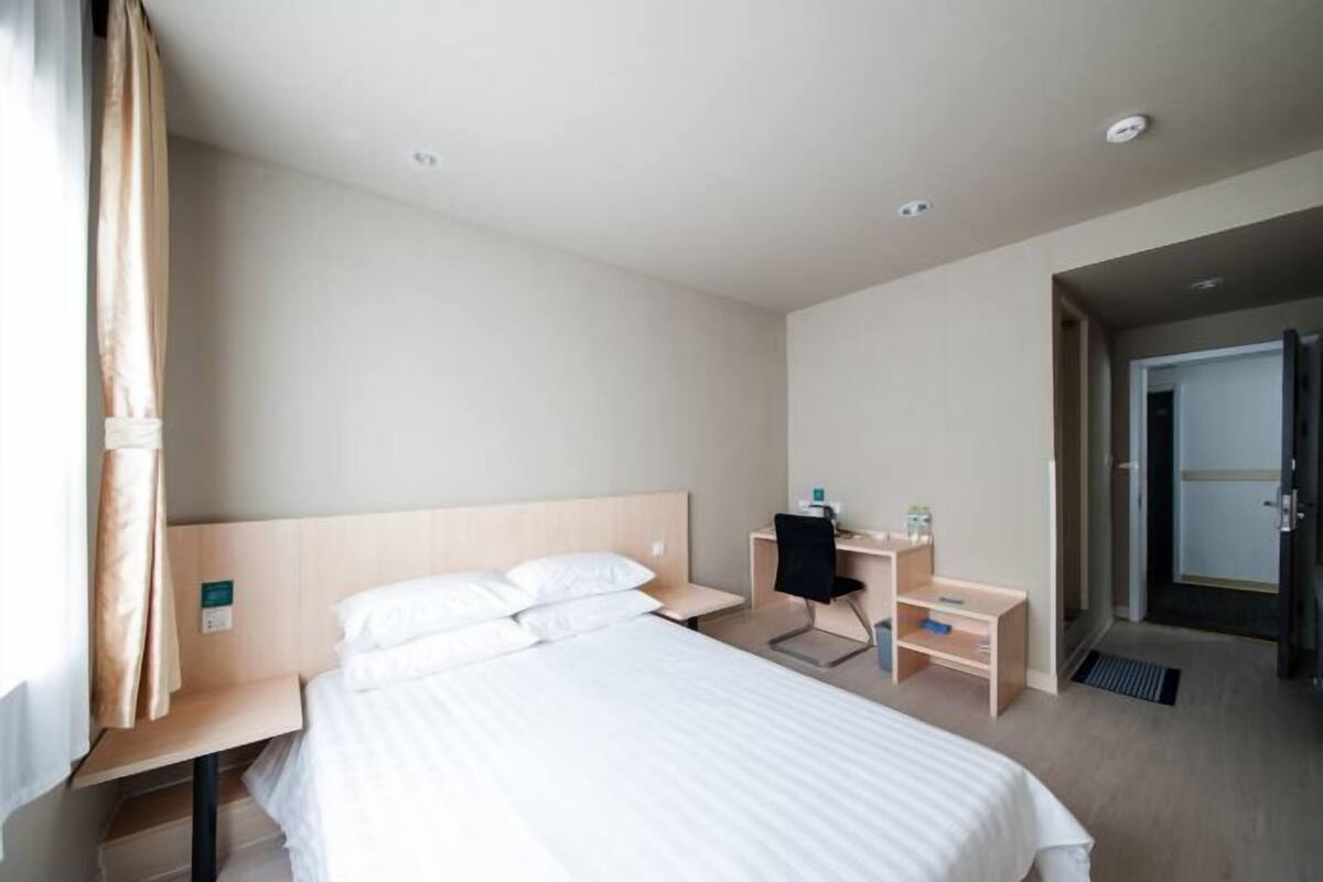 Una habitación de hotel con cama, escritorio, silla y puerta.