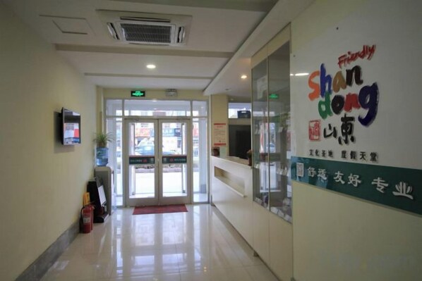 A hotel lobby with a reception desk, a glass wall, and a signboard.