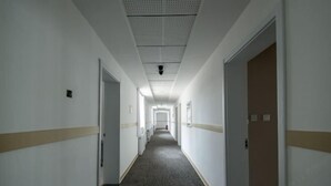 En lång, smal hotellkorridor med vita väggar och ett mönstrat golv.