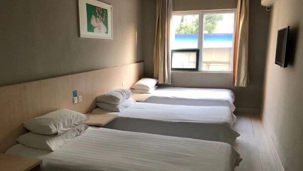 Ett hotellrum med tre separata sängar, ett fönster med utsikt över stranden och en platt-TV på väggen.