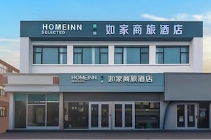 Un edifici de dues plantes amb un rètol que diu 'HOMEINN SELECTED' i '如家商旅酒店'.