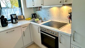 A compact kitchen with white cabinets, a built-in oven, and a stovetop.