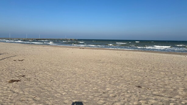 A beach with a pier in the background.
