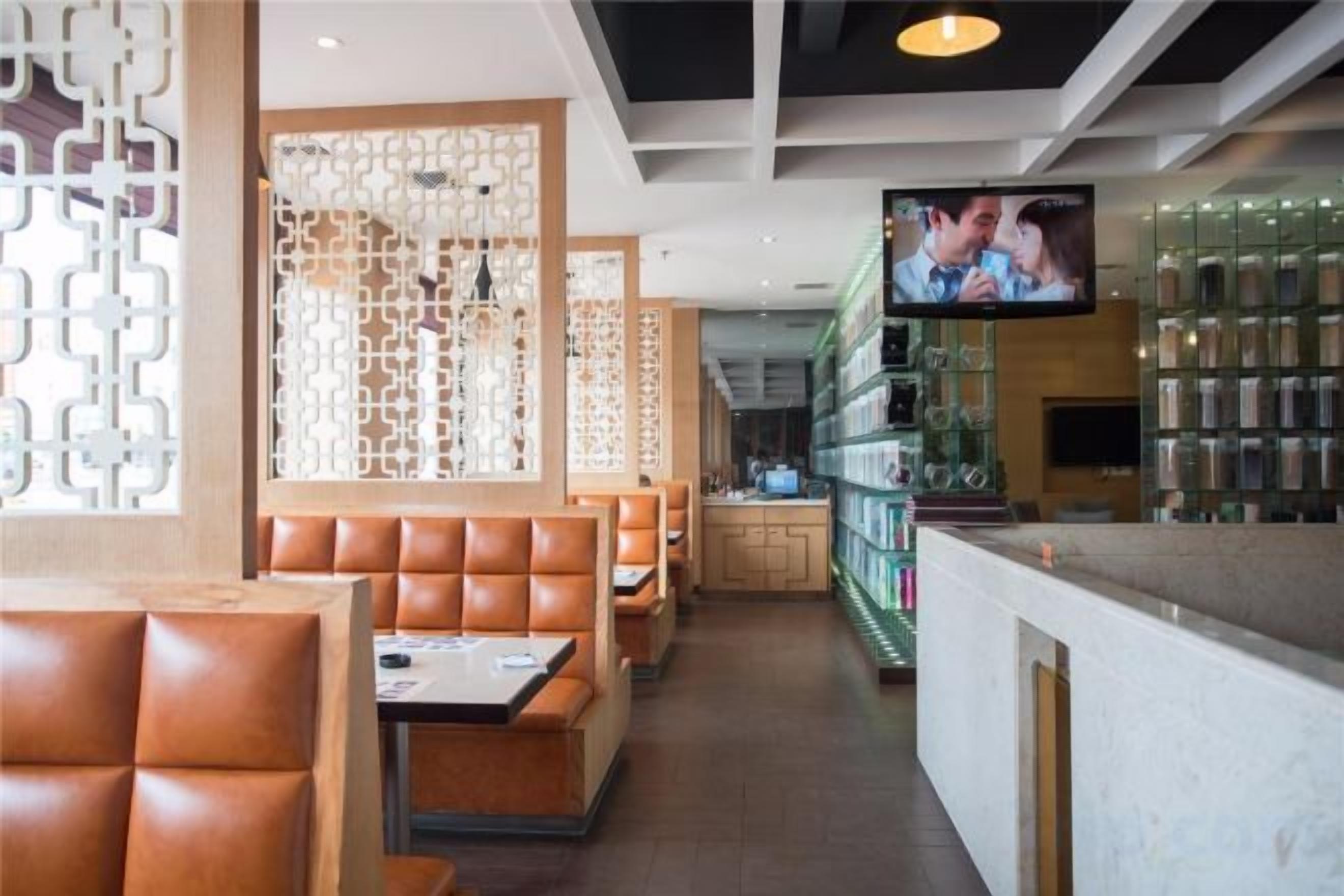 Un restaurante con cabinas, una zona de bar y una pantalla de televisión.