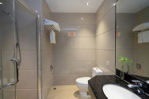 A modern bathroom with a glass shower enclosure, a toilet, and a sink with a mirror. - Dong Chang Hotel (Dongguan Hengli China Resources Shopping Plaza) (Dongguan)