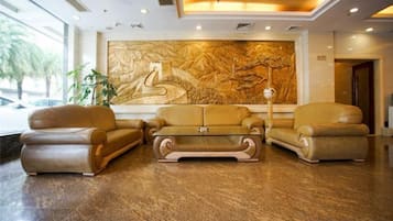 A lobby with a large wall mural, leather sofas, and a coffee table.