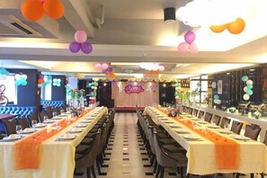 A banquet hall with long tables set for dining, a stage with floral decorations, and a bar area. - Dong Chang Hotel (Dongguan Hengli China Resources Shopping Plaza) (Dongguan)