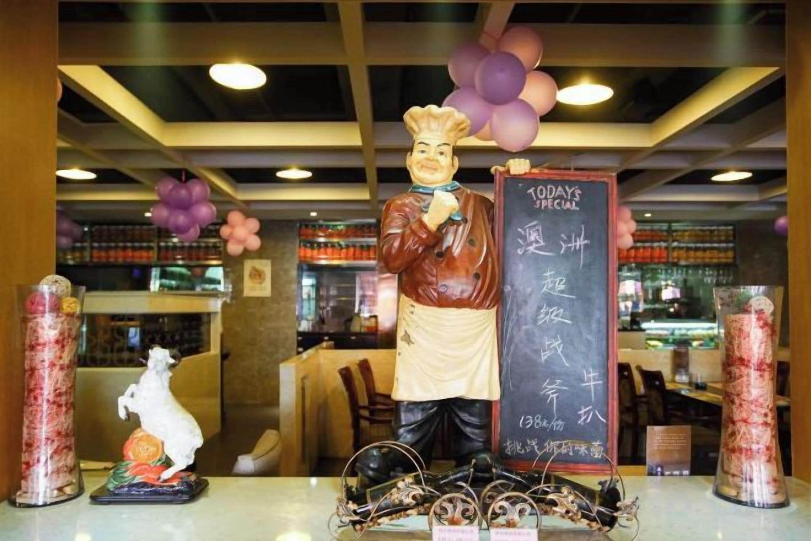 A restaurant interior with a chef statue, a chalkboard menu, and decorative elements.