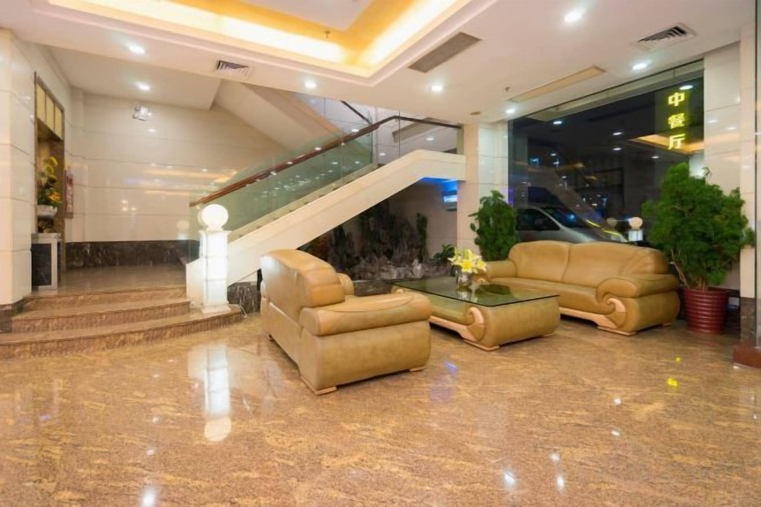 Un vestíbulo con una escalera, un conjunto de sofás y un mostrador de recepción.