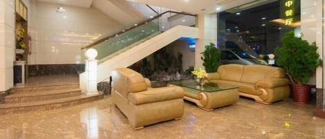 Un vestíbulo con una escalera, un conjunto de sofás y un mostrador de recepción.
