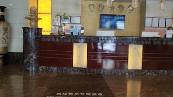 A reception desk with a marble top, a digital screen, and a decorative vase.