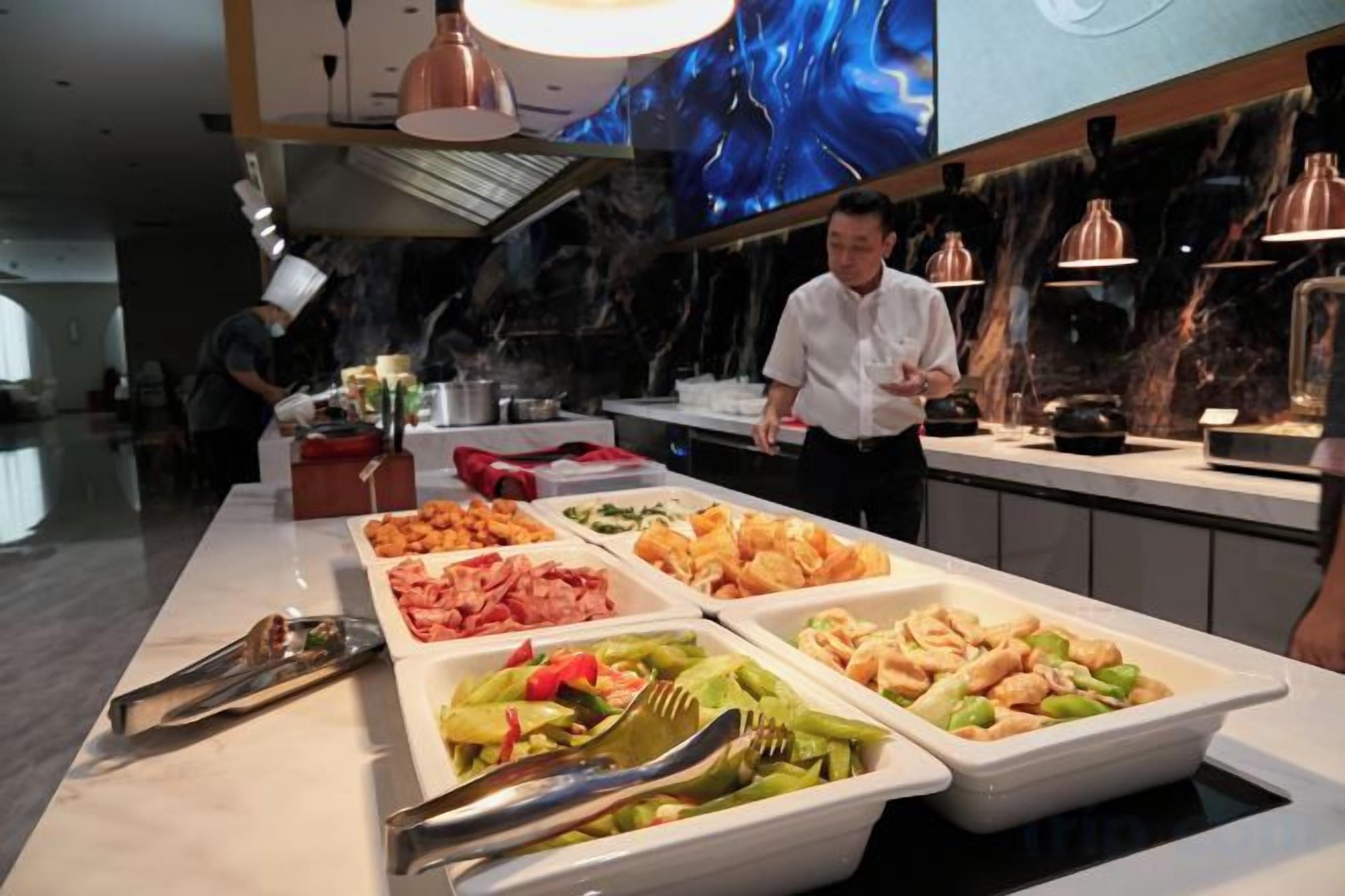 A buffet with various food options and a chef in the background.