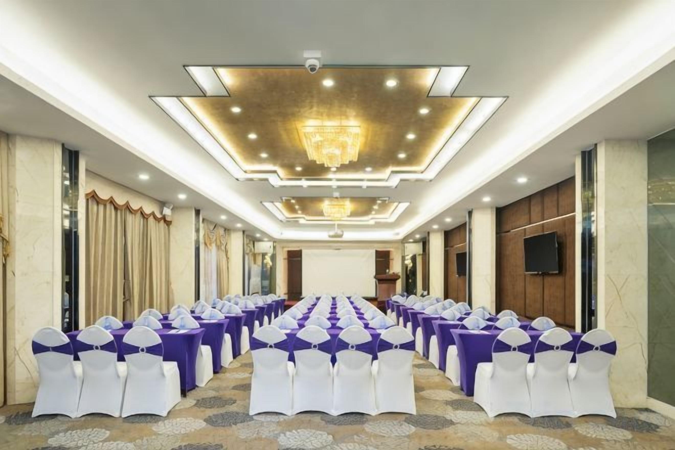 A conference room with rows of chairs, a chandelier, and a podium.