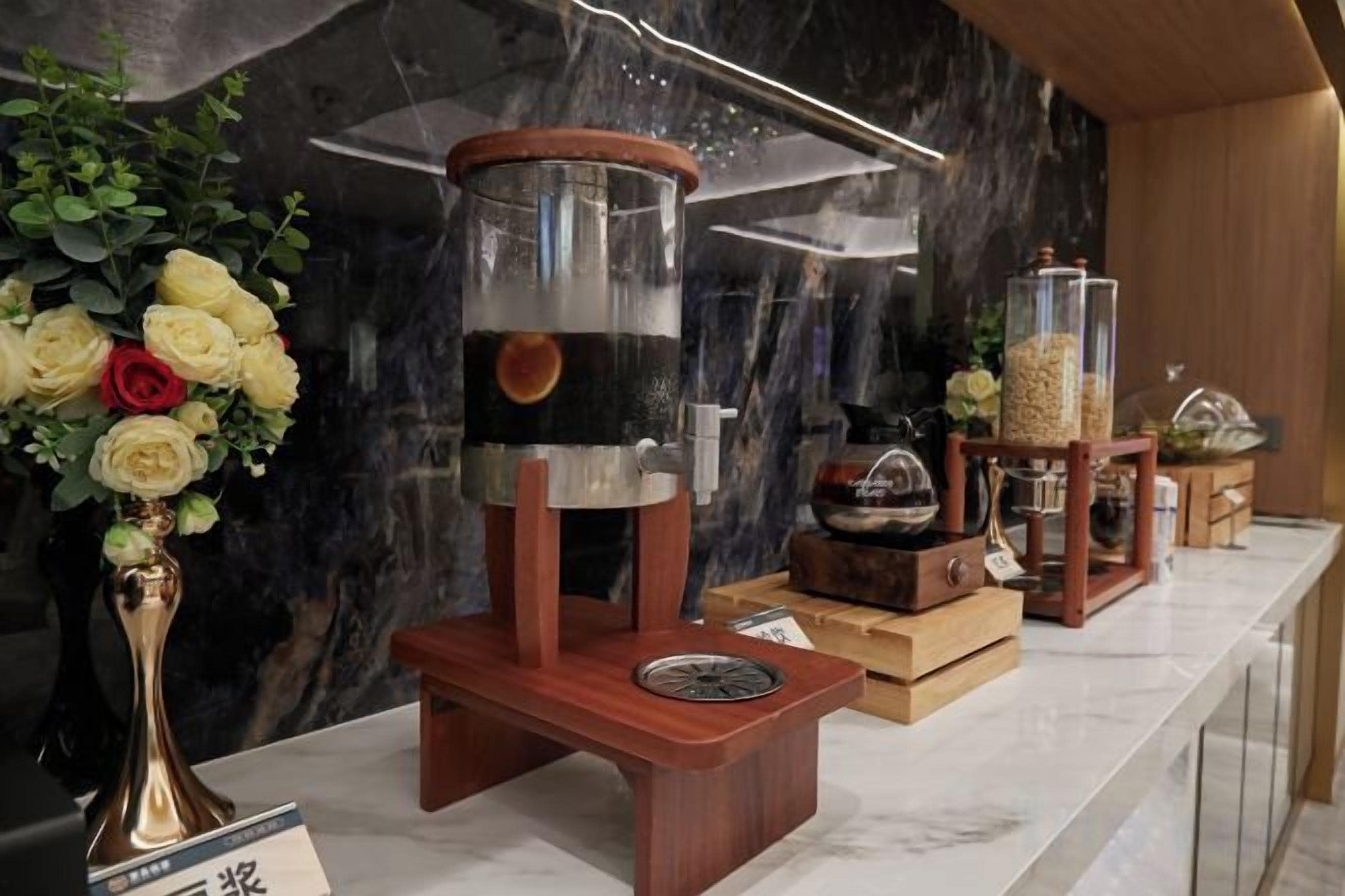 A coffee station with a coffee grinder, a coffee pot, and a glass container of coffee beans.
