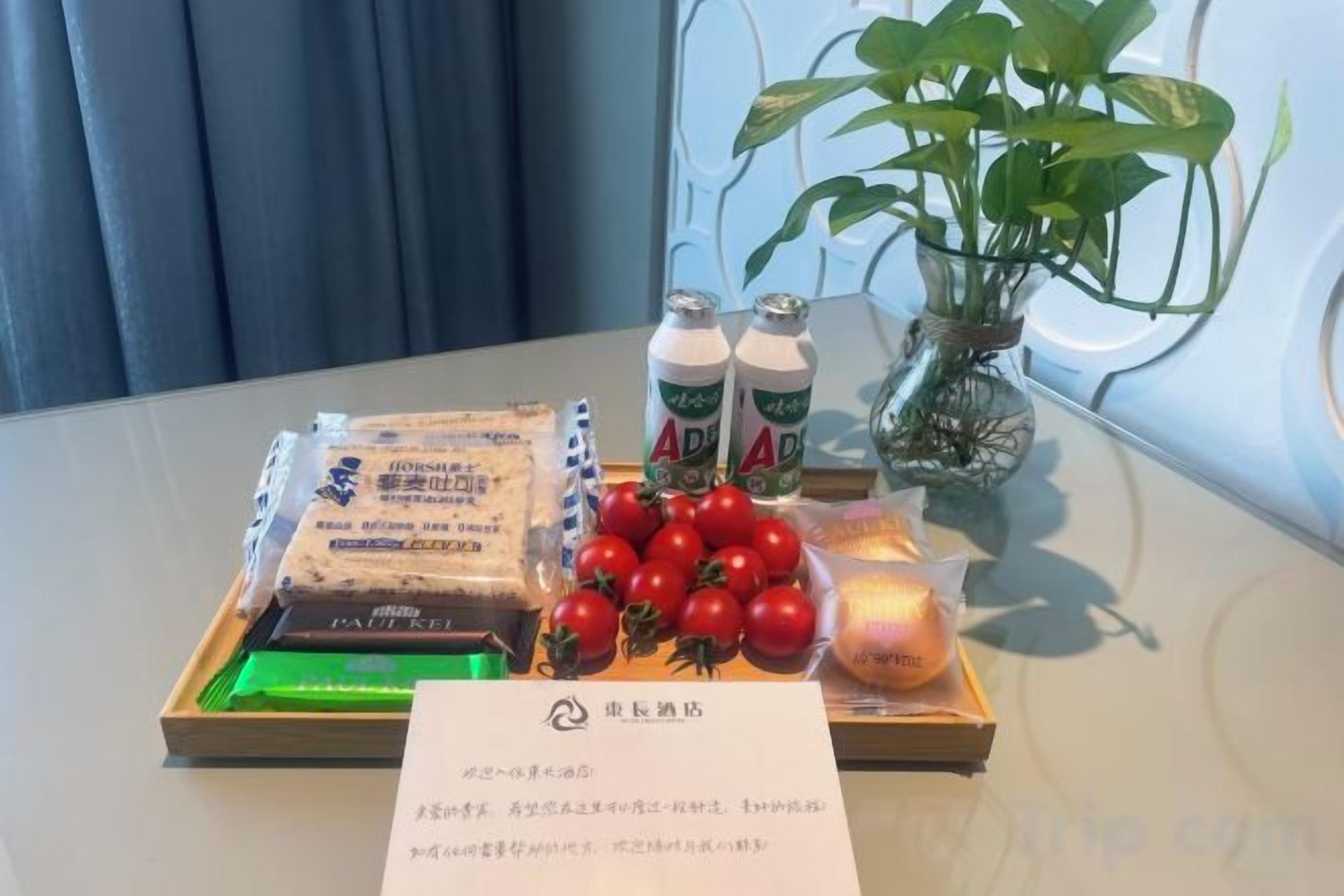 A tray with snacks, drinks, and a candle on a table.