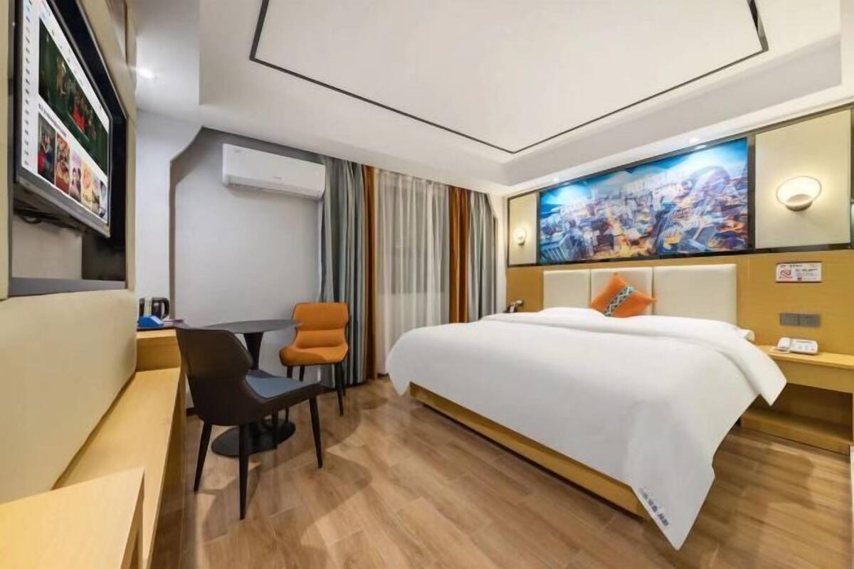 Una habitación de hotel con una cama, un escritorio, una silla y un televisor.