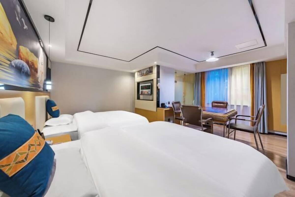Habitación de hotel con cama, escritorio y silla. Hay un cuadro en la pared y una ventana con cortinas.