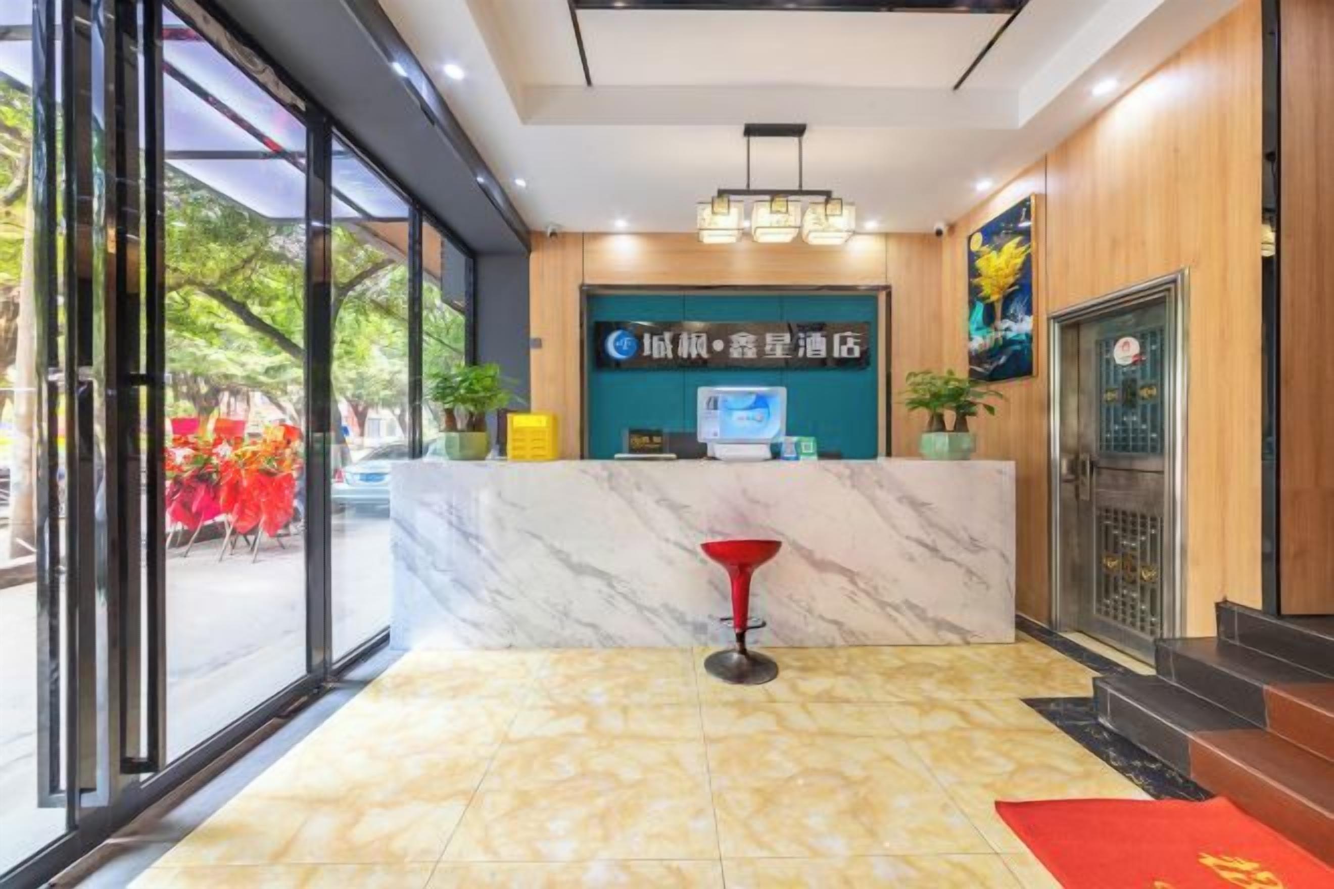 A hotel reception area with a marble counter, a red bar stool, and a digital screen displaying the hotel name.