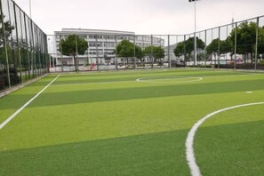 Un campo deportivo con un arco, rodeado por una valla, y un edificio al fondo.