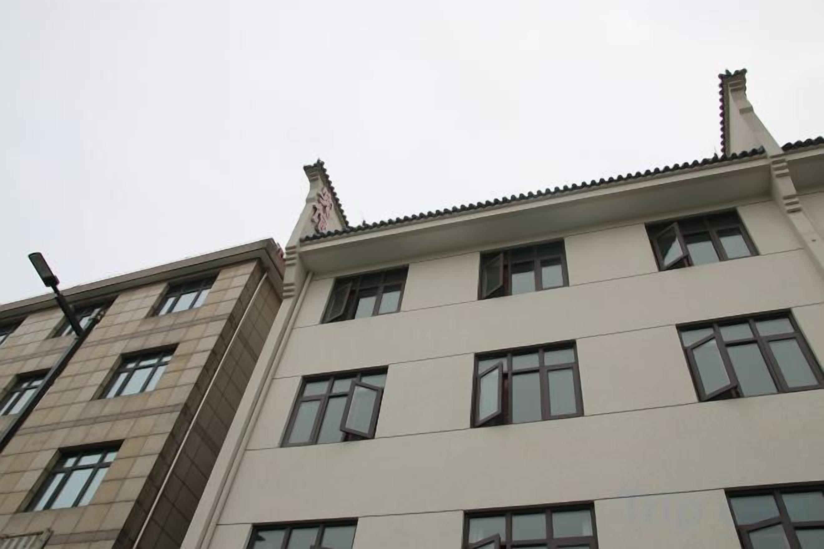 Un edificio de varios pisos con fachada plana, múltiples ventanas y una chimenea.