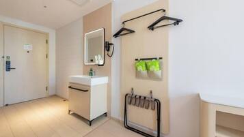 Habitación de hotel con tocador blanco, espejo, toallero y calentador de toallas en la pared.