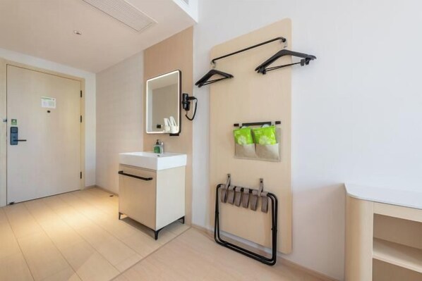 Ein Hotelzimmer mit weißem Schminktisch, einem Spiegel, einem Handtuchhalter und einem wandmontierten Handtuchwärmer.