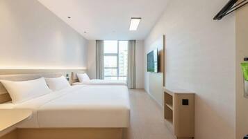 Una habitación de hotel con una cama grande, una mesita de noche, un televisor montado en la pared y una ventana con cortinas.