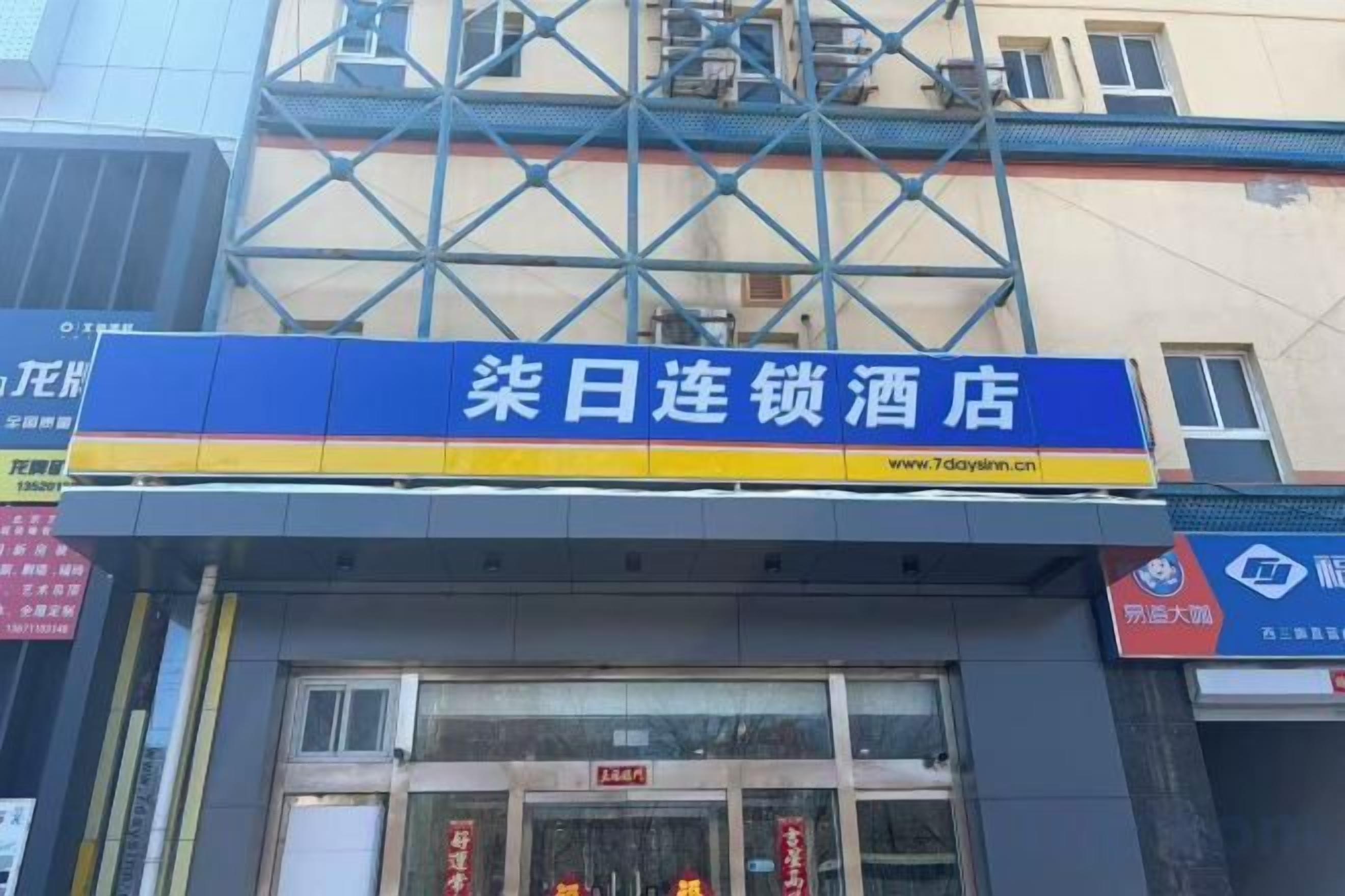 A hotel with a blue signboard, a visible entrance, and a window with a red sign.