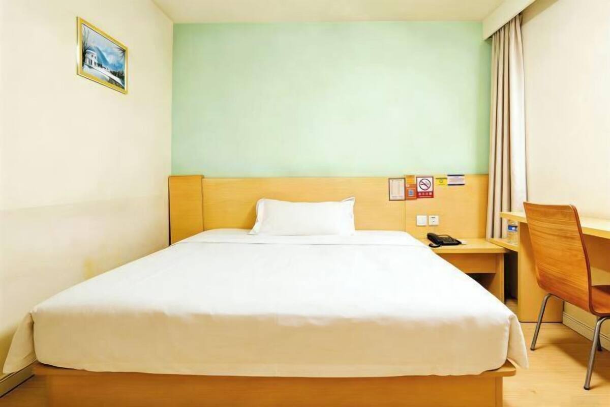 Une chambre d’hôtel avec un lit, un bureau, une chaise et un tableau au mur.
