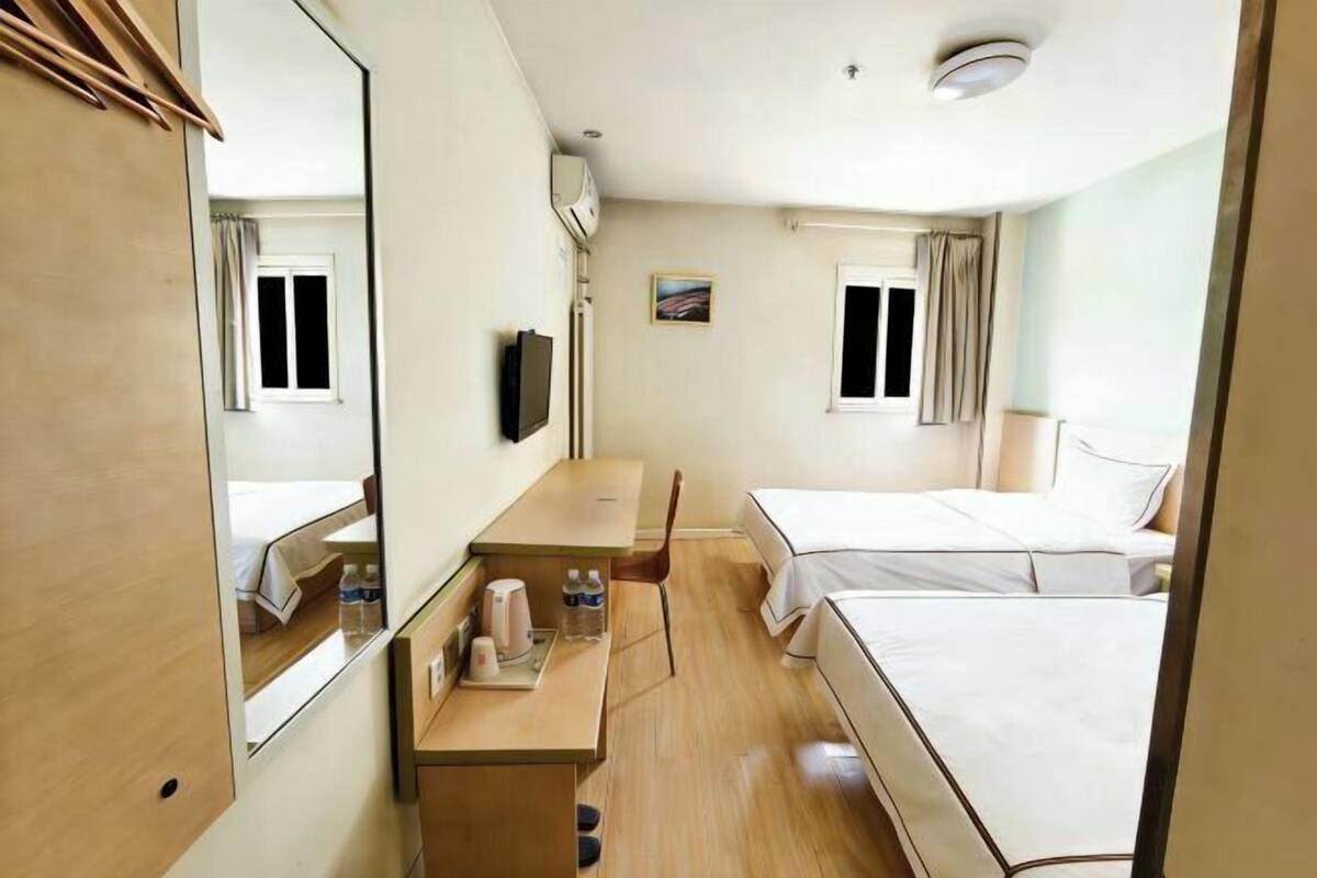 Une chambre d’hôtel avec un lit, un bureau et une chaise, une télévision et une fenêtre.