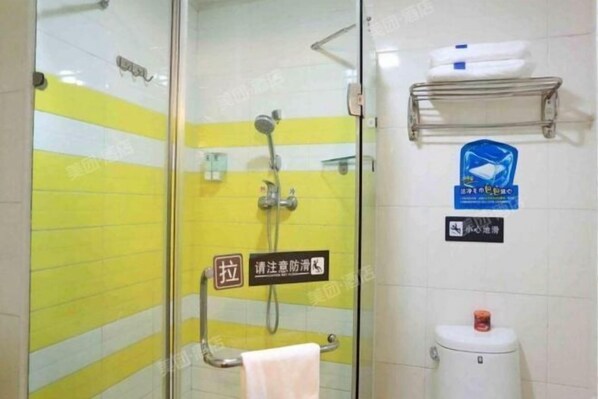 Une salle de bain avec une paroi en verre, une douche, des toilettes et un porte-serviettes.