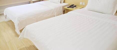 Quarto de hotel com duas camas, uma mesa com computador, telefone e uma placa na parede.