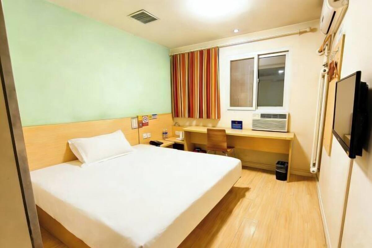 Une chambre d’hôtel équipée d’un lit, d’un bureau, d’une chaise, d’une fenêtre et d’un téléviseur.