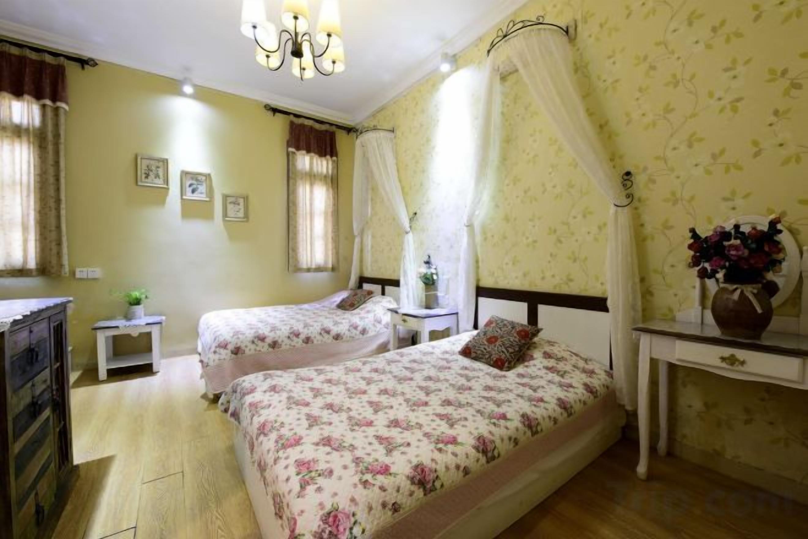 A bedroom with two beds, a nightstand, a dresser, and a bedside table with a lamp.