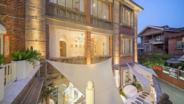 A multi-story building with a courtyard, featuring a pool, outdoor seating, and a staircase. - UUINN Villa (Xiamen)