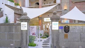 A hotel entrance with a stone gate, a signboard, and a canopy. - UUINN Villa (Xiamen)