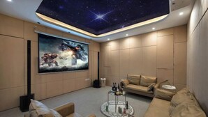 A modern living room with a starry ceiling, a large movie poster, and comfortable seating. - UUINN Villa (Xiamen)