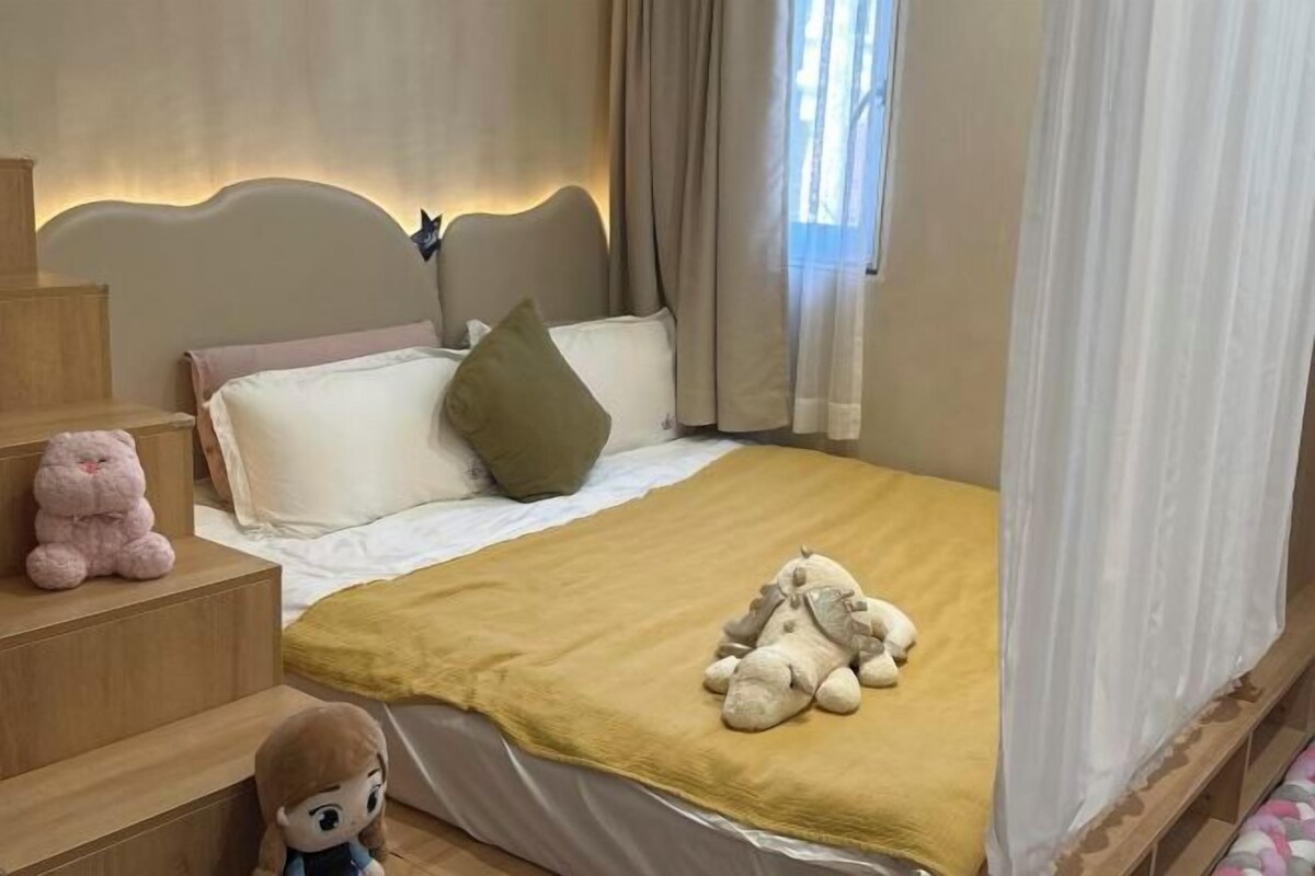 A bedroom with a bed, a nightstand, a plush toy, and a window with curtains.
